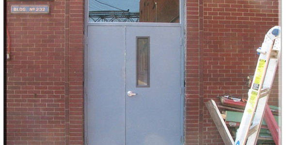 A blue door in front of a brick building.
