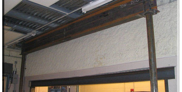 A metal beam is hanging over a ceiling in a warehouse.