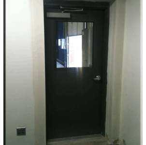 A black door in a room that is under construction.