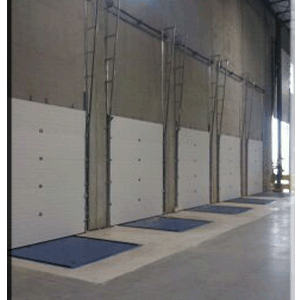 A group of garage doors in a warehouse with blue mats.
